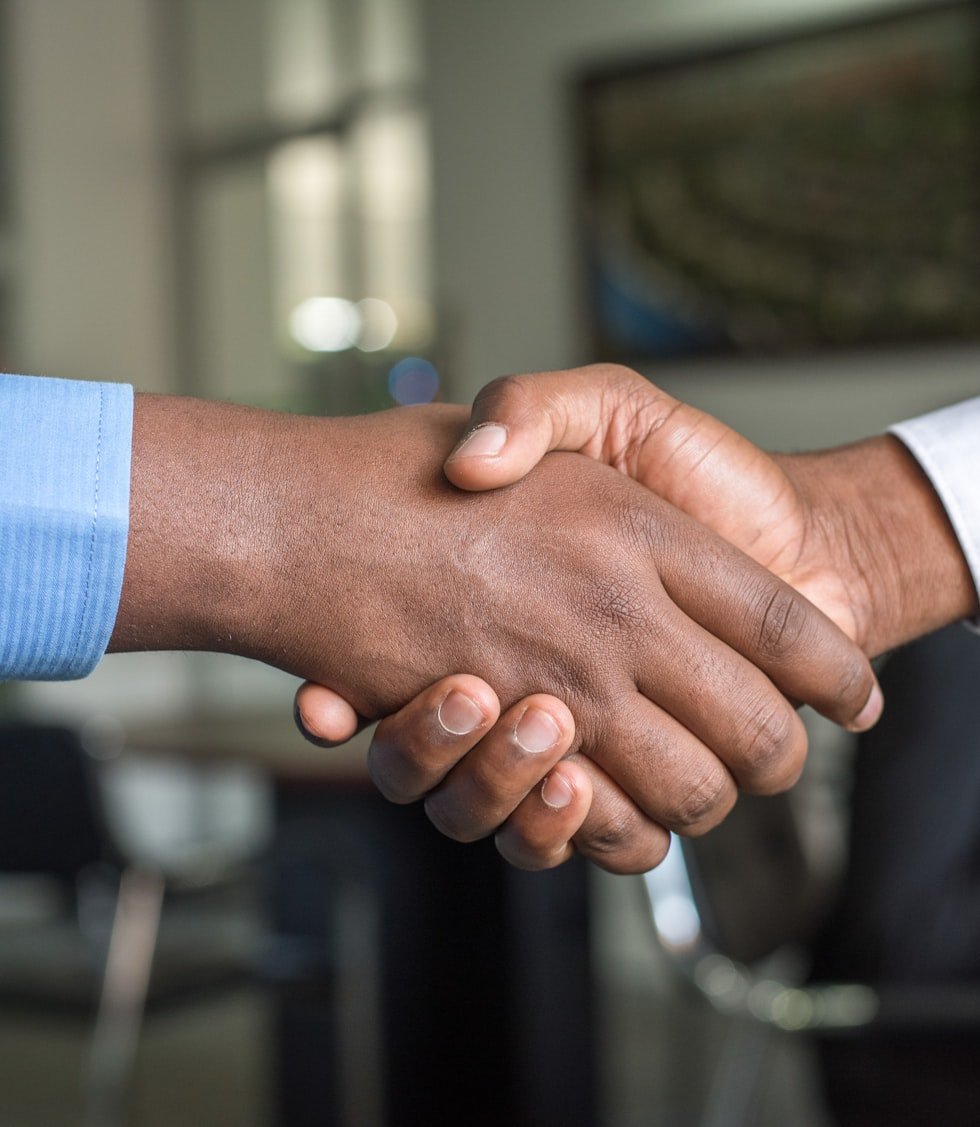 Two people shaking hands across a desk